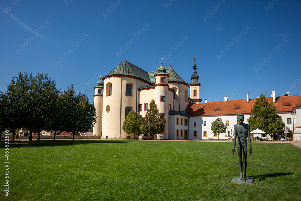 Gothic medieval church, Piarist Church of the Finding of the Holy Cross at sunny summer day, Monastery Garden with sculptures, Litomysl, Czech Republic
