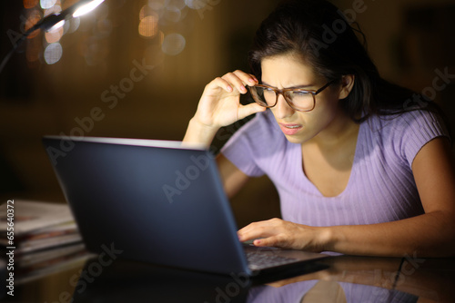 Woman using eyeglasses forcing sight with laptop in the night