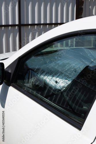 A sun reflector inside a white car parked in the yard. Solar reflector protects the plastic of the car from heating.