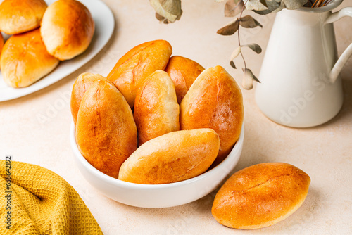 Pirozhki, piroshki. Homemade baked yeast leavened boat shaped buns with braised cabbage fillings. Pirozhki are a popular street food and comfort food in Eastern Europe. Light background. photo