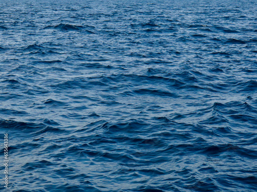 Blue water surface. Blue water background. Waves on the surface of the ocean. Slight disturbance on the surface of the sea.