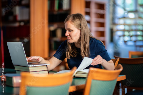 A visually impaired young woman sitting and studying in the university library