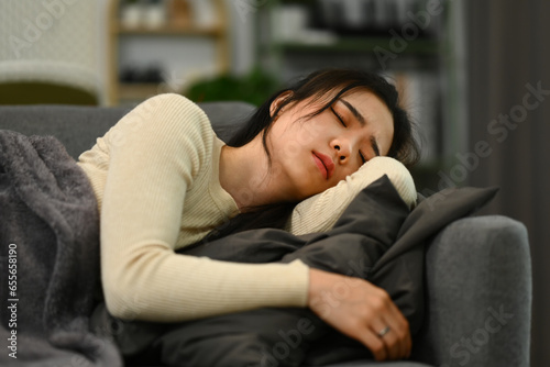 Sick woman lying on couch under blanket feeling exhaustion, suffering from headache, flu symptom