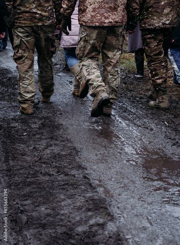 Men in military uniform walk down the road after the rain. Soldiers return home. Dramatic background, cold colors. Concept of war and peace