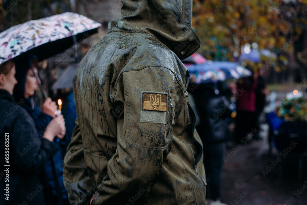 A Ukrainian serviceman in the rain at the funeral of his comrade who died during Russia's invasion of Ukraine. Dramatic background, cold colors. Concept of war and peace