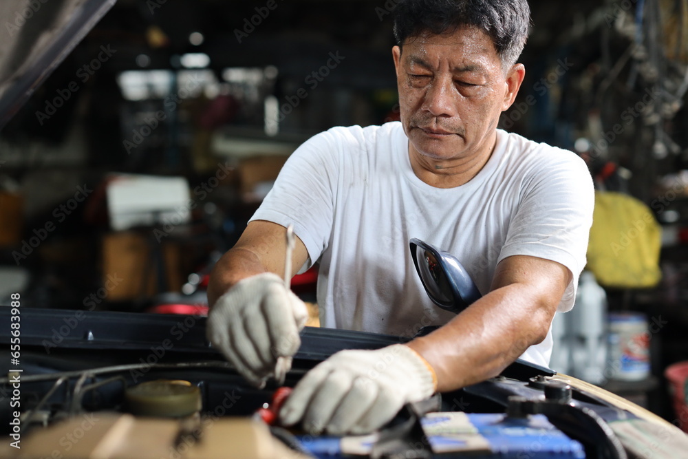 Man technician car mechanic in half uniform checking maintenance a car service at repair garage station. Worker holding wrench and fixing breakdown vehicle. Concept of car center repair service. Man technician car mechanic in half uniform checking maintenance a car service at repair garage station. Worker holding wrench and fixing breakdown vehicle. Concept of car center repair service.