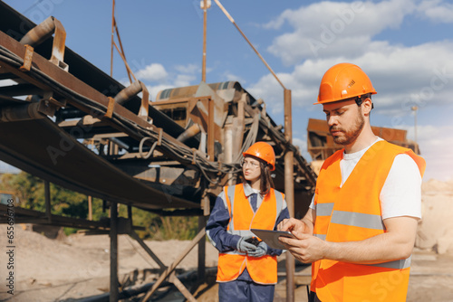 Engineer Worker use computer tablet for control quarry industrial excavator on construction site or open pit mine sand