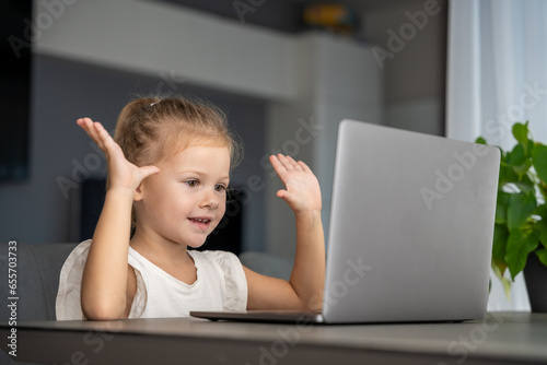 Little girl does finger gymnastics online on the laptop home. Distance learning concept.