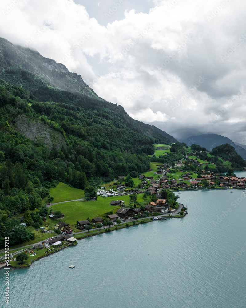 Aerial view of Iseltwald, a small town along the Brienzersee Lake coastline in summertime with rain and low clouds, Bern, Switzerland. Aerial view of Iseltwald, a small town along the Brienzersee Lake coastline in summertime with rain and low clouds, Bern, Switzerland.