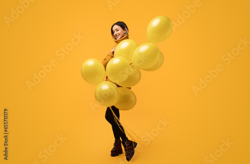 Happy young woman with yellow balloons in studio