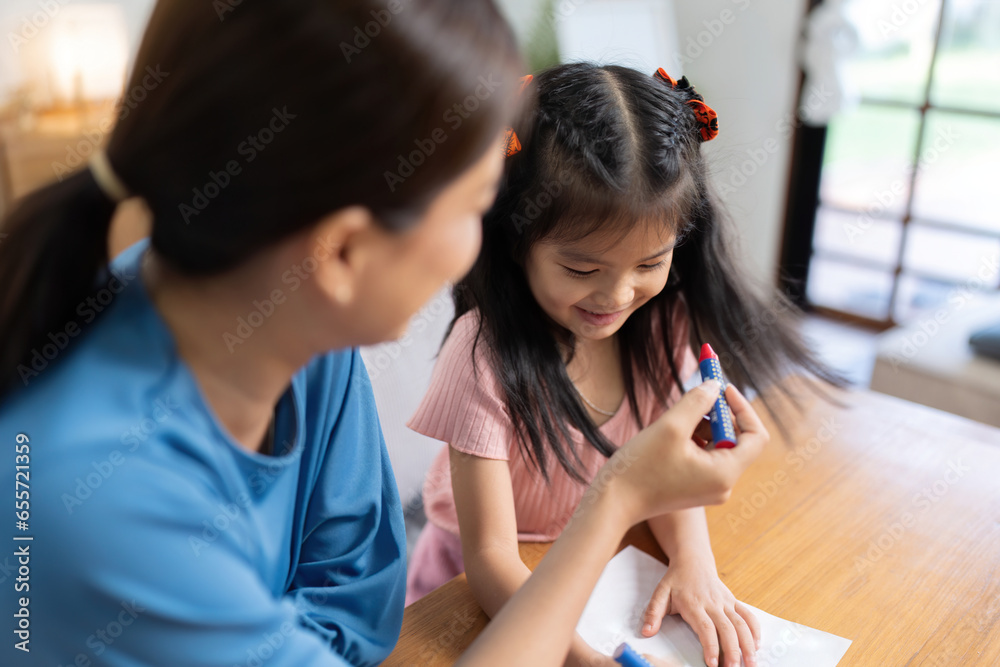 Happy family mother and daughter study or draw together at home in living room Happy family mother and daughter study or draw together at home in living room