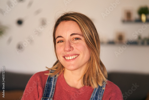 Close up portrait of beautiful young Caucasian woman smiling happy. Blonde nice female looking cheerful at camera. Joyful girl indoors in positive aptitude. Natural beauty in millennial generation.