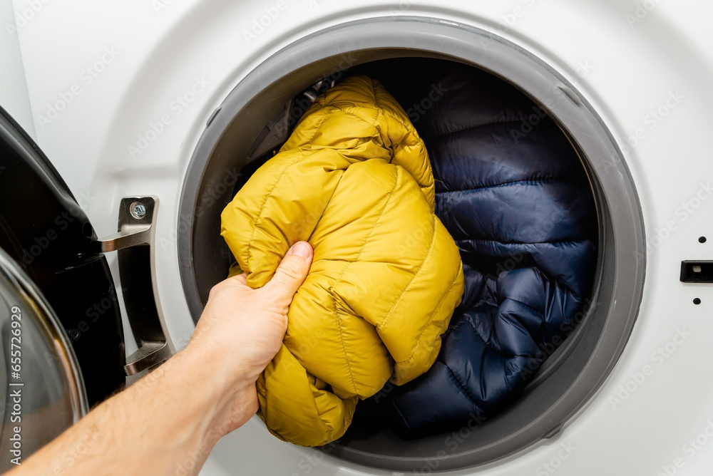 Foto de Putting winter puffer jacket into the drum of open washing