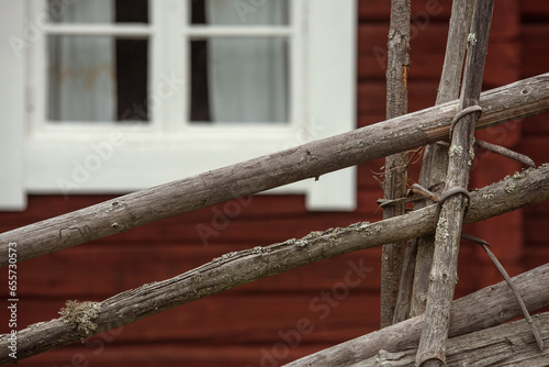 An old picket fence in front of the red log cabin