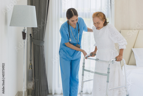 Obraz na płótnie Asian elderly woman practice walking using walker aid with nurse care support st