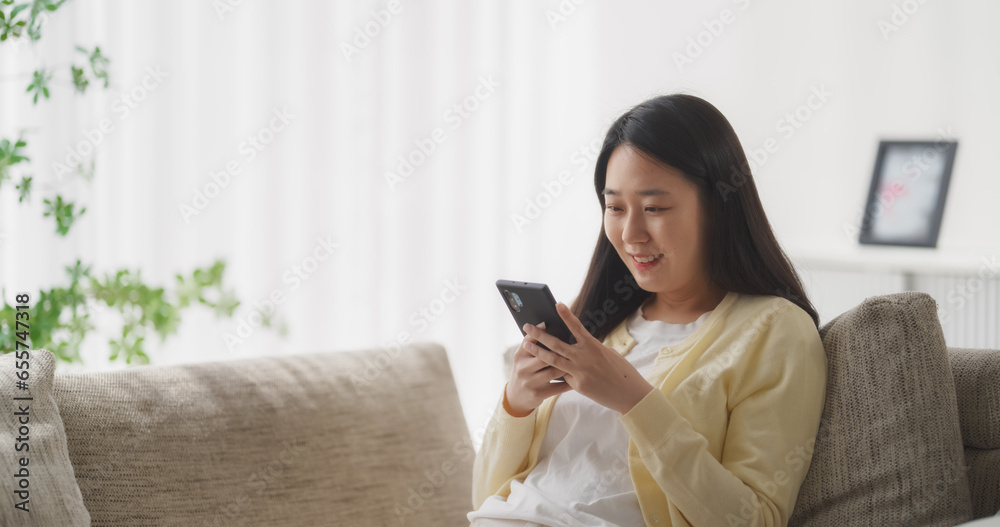 Young South Korean Woman Engaged and Connected Online, Enjoying Leisure Time with Her Smartphone, Spending Time Resting on a Sofa and Exploring Social Media and Entertainment Apps Young South Korean Woman Engaged and Connected Online, Enjoying Leisure Time with Her Smartphone, Spending Time Resting on a Sofa and Exploring Social Media and Entertainment Apps