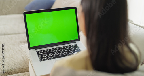 Anonymous Young Female Doing Creative Work on a Laptop Computer with Green Screen Mock Up Display. Bringing Ideas to Life in the Comfort of Her Modern Home Environment. Over the Shoulder Footage