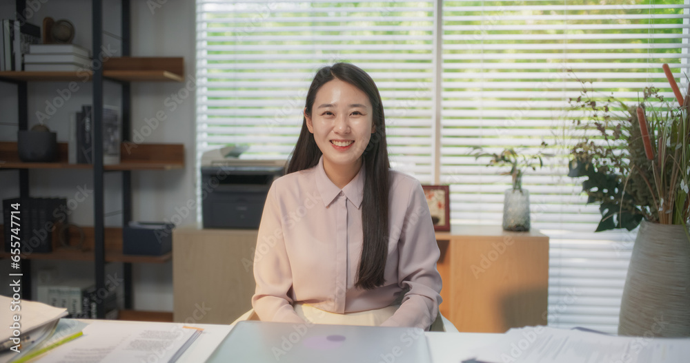 Portrait of Beautiful Korean Female Working on Laptop Computer in her Modern Office. Young Creative Manager Feeling Happy, Looking at Camera and Smiling. Successful Businesswoman Working from Home