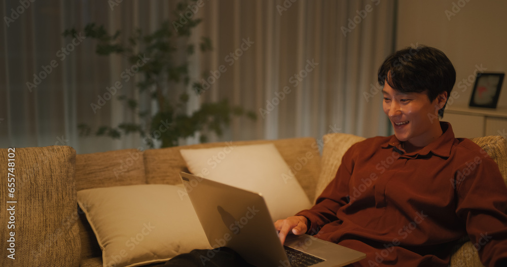 Handsome South Korean Man Resting on a Sofa at Home, Using Laptop ...