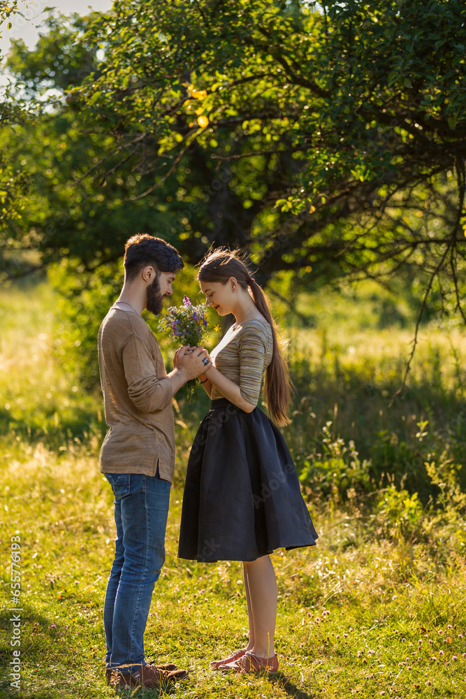Fototapeta premium couple in nature with wildflowers, smelling a bouquet