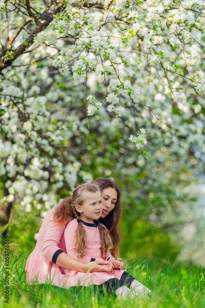 mother and daughter walk through a blooming apple orchard mother and daughter walk through a blooming apple orchard