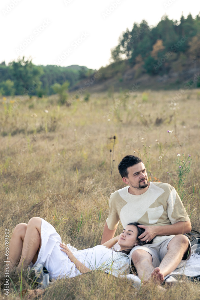 Happy married man and woman on a date relaxing in the field.