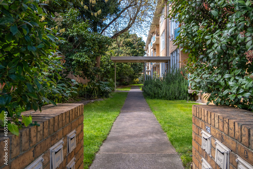 A footpath or walkway leads to the entrance of the residential units building with mailboxes on sides. Concept of Australian housing market, real estate investment and a suburban neighbourhood. 