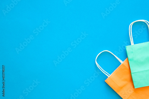 Paper bags of different colors on a blue background, top view.