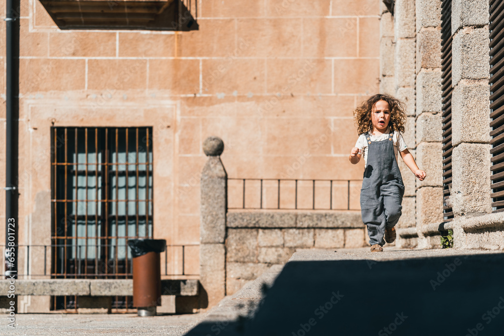 little model boy running happy through world heritage streets in Cáceres