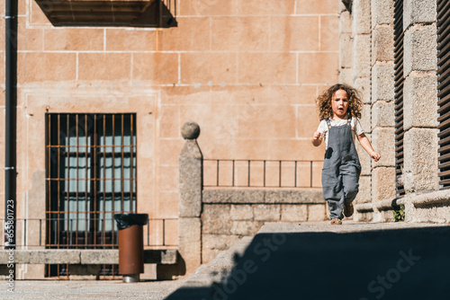 little model boy running happy through world heritage streets in C  ceres
