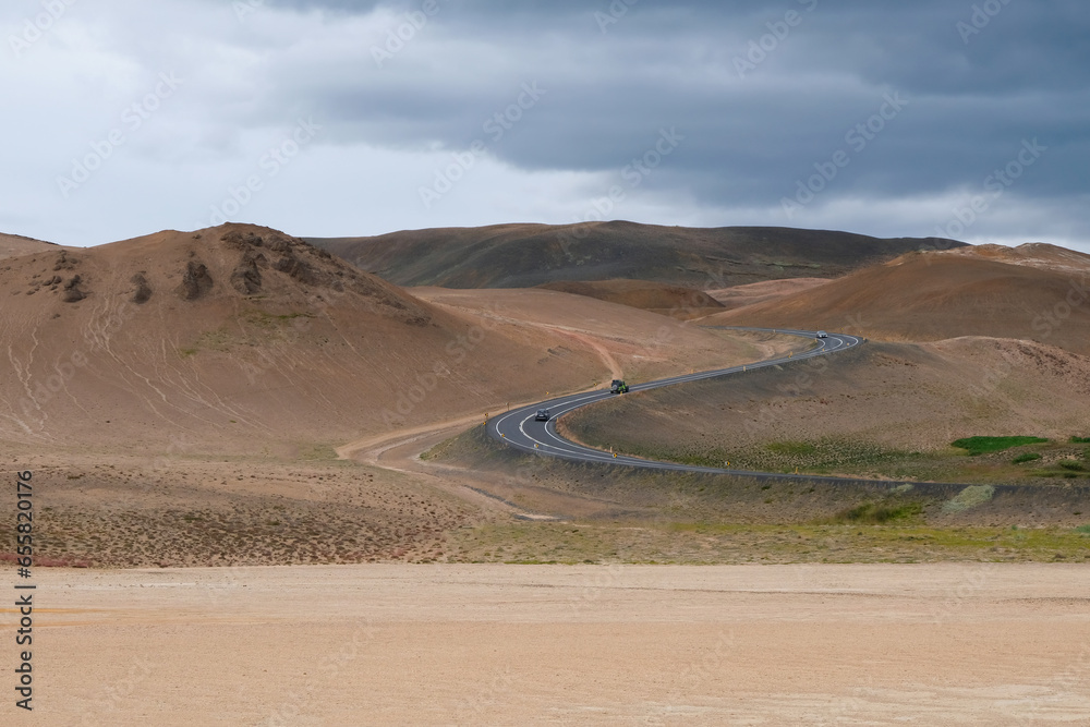 A mountain asphalt road leads to mountains in the volcanic zone in northern Iceland.
