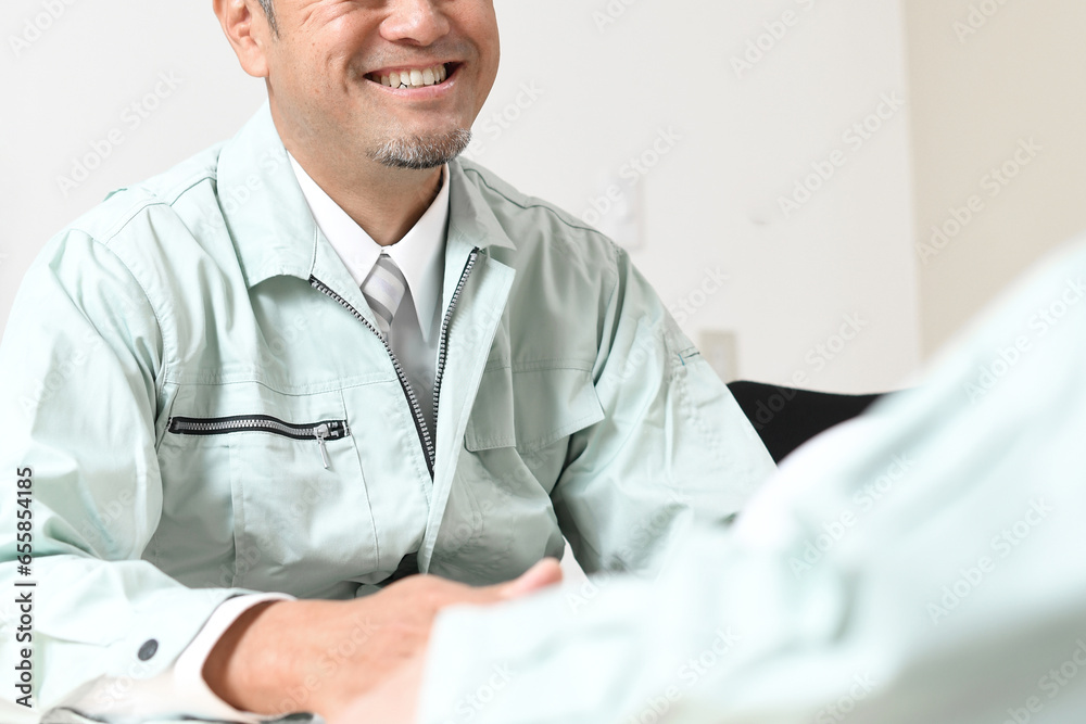 オフィスで会話をする笑顔の中年の男性作業員達
オフィスで会話をする笑顔の中年の男性作業員達