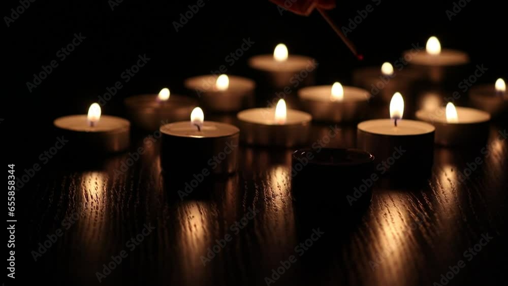 An extinguished candle and a woman s hand lights the candle with a match. Bright candlelight, funeral or meditation, winter mood, cozy atmosphere. An extinguished candle and a woman s hand lights the candle with a match. Bright candlelight, funeral or meditation, winter mood, cozy atmosphere.