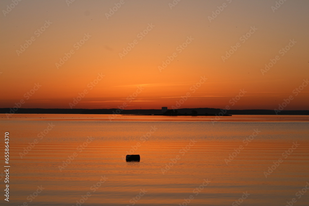 Orange sunset over the water. A beautiful fabulous horizon and the setting sun over the lake. Evening seascape.