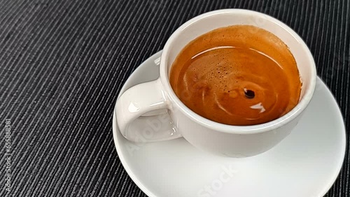 coffee drop falling in super slow motion inside of cup of espresso italian coffee with foam on black background, food and drink and relax photo