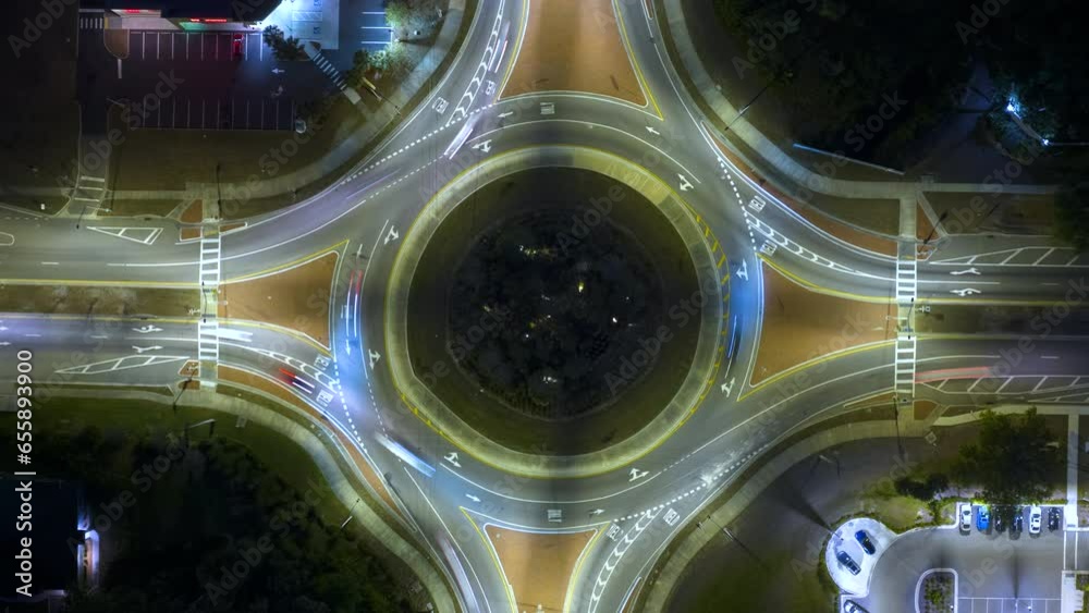 Top view of city street traffic on roundabout intersection at night with fast moving cars. Timelapse of illuminated urban circular transportation crossroads