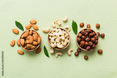 Assortment of nuts in wooden bowl on colored table. Cashew, hazelnuts, walnuts, almonds. Mix of nuts Top view with copy space