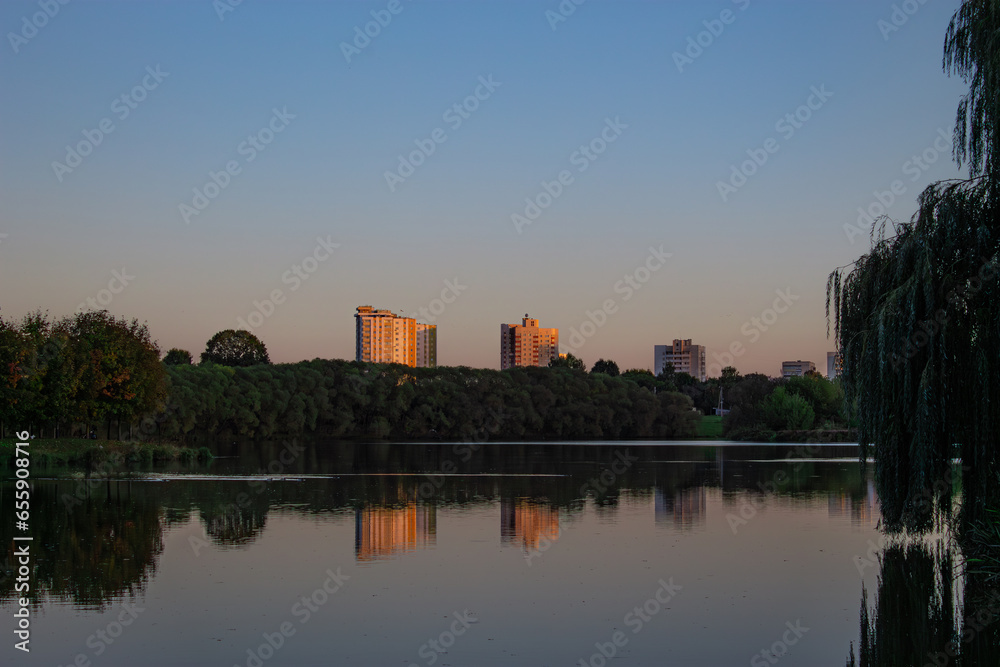 Lake in the city park. Sunset in a city park by the river. reflection of buildings in water