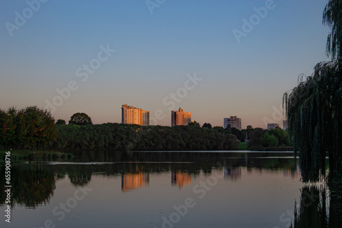 Lake in the city park. Sunset in a city park by the river. reflection of buildings in water