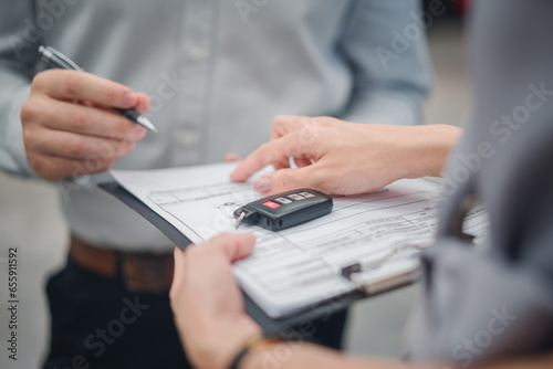 Car sale or rental concept, Closeup Dealership manager signing car insurance document or lease paper contract. Customer with car dealer agent making deal, sign on agreement document contract in office photo
