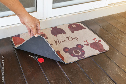 Man revealing hidden key under doormat.