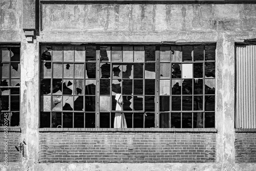 A black and white image of a window with broken glass in an old manufacturing building in the south city of Saint Louis, Missouri.