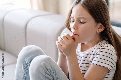 Girl sitting on sofa, feeling bad and suffering from dry cough