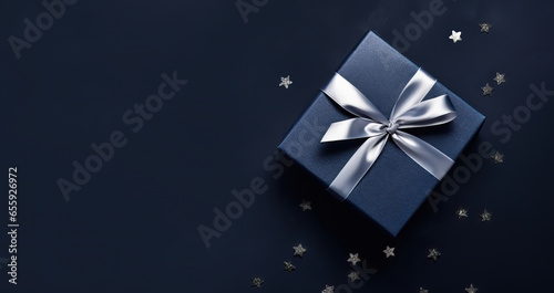 Elegant Dark blue gift box with silver satin ribbon on dark background. Top view of greeting gift with copy space for Christmas present, holiday or birthday