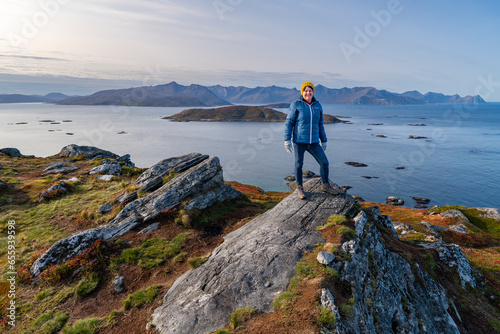 hiking woman on hill, autumnal nature of Norway. Hiking by the fjord and mountains on the island of Kvaløya in Troms, between orange and red colored plants and birch. place to relax, hikers paradis photo