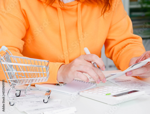 Inflation. Woman uses calculator to calculate expenses for shopping. Receipts and household expenses