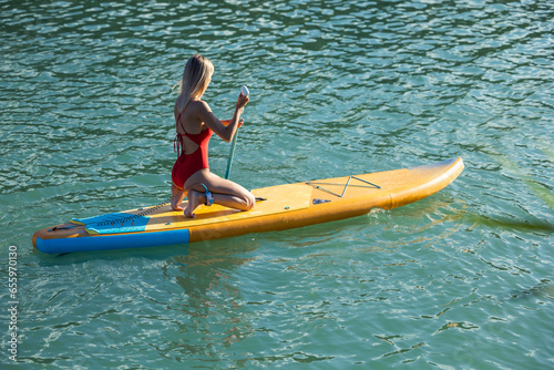 Woman paddling on sup board in blue ocean. © zinkevych