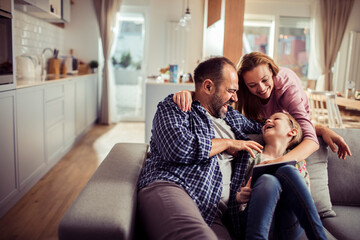 Happy young caucasian family being playful and having fun on the couch at home