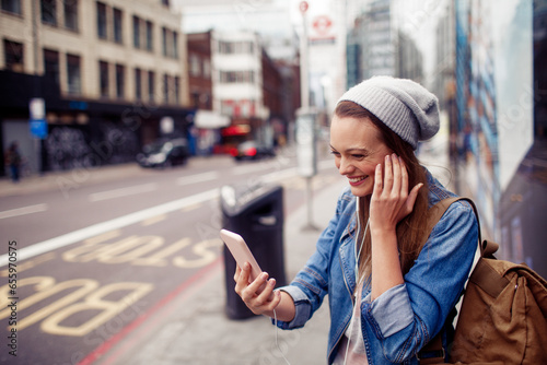 Happy young caucasian woman using a phone on a city street