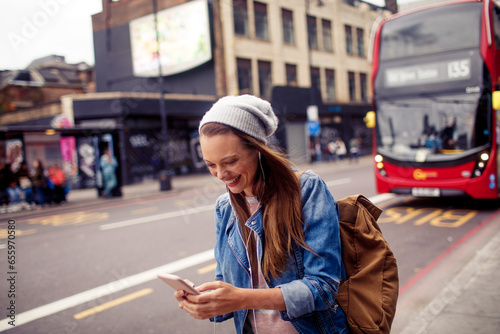 Happy young caucasian woman using a phone on a city street